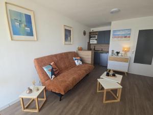 a living room with a brown couch and two tables at Escale au Port du Crouesty in Arzon