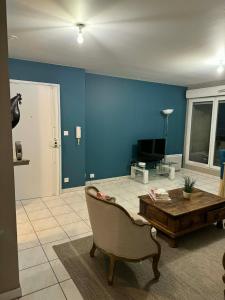 a living room with blue walls and a table and a chair at Apt Parisien in Vitry-sur-Seine
