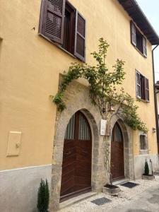 a building with two brown doors and a tree at I due archi in Norcia