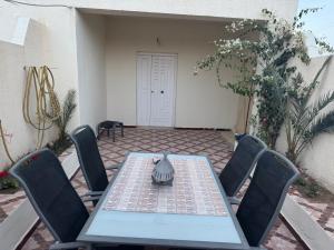 a table with chairs and a vase on top of it at Aghir DJERBA Erdgeschosswohnung in Al Ḩaddādah