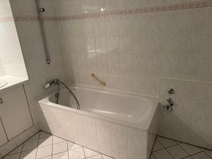 a white bath tub in a tiled bathroom at Stay Zentral Dresden in Dresden