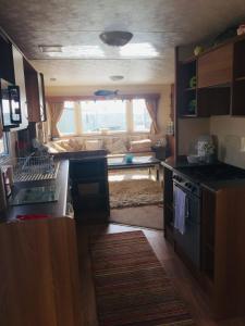 a kitchen with a stove and a living room with a couch at Paddocks 4 in East Mersea