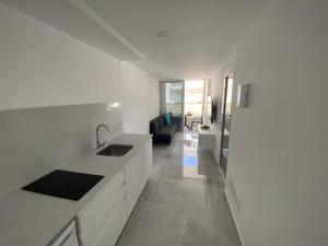 a white kitchen with a sink and a living room at Alaram Holidays House by Villas Rivero in Arguineguín