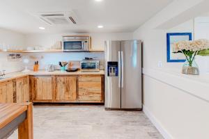 a kitchen with a stainless steel refrigerator and wooden cabinets at Seas the Day OBX in Kitty Hawk Beach +7 photos
