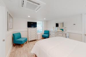 a bedroom with a white bed and two blue chairs at Seas the Day OBX in Kitty Hawk Beach