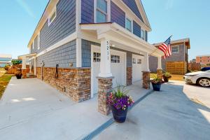 a house with an american flag and flowers in a driveway at Seas the Day OBX in Kitty Hawk Beach