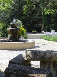 a fountain in the middle of a park with flowers at Le Moulin Des Ocres in Apt