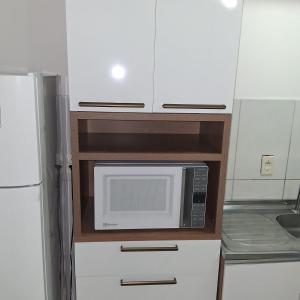 a microwave in a kitchen with white cabinets at Apartamento no Antares in Maceió