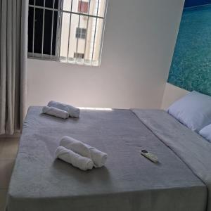 a bed with two towels on it with a window at Apartamento no Antares in Maceió