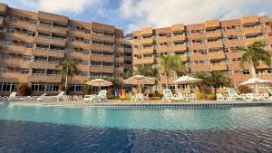a swimming pool with chairs and umbrellas in front of a building at Gran Lençóis Flat - Barreirinhas -MA in Barreirinhas