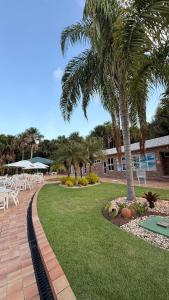 a patio with tables and palm trees in a resort at Gran Lençóis Flat - Barreirinhas -MA in Barreirinhas