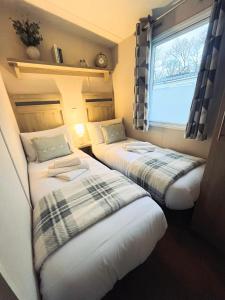 two beds in a small room with a window at Snug on the Teviot in Hawick