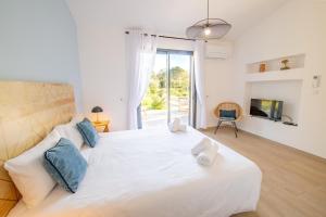 a bedroom with a large white bed and a tv at Villa Ena in Figari