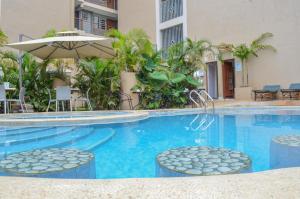 a swimming pool with two chairs and an umbrella at Shelvic Resort Ruiru in Ruiru