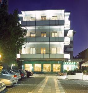 a tall building with cars parked in a parking lot at ACasaMia WelcHome Hotel in Rimini