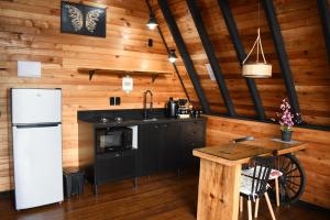 a kitchen with a white refrigerator and a wooden wall at Chalé Encanto Do Lago in Urubici