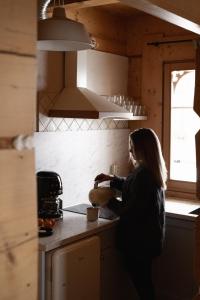 a woman in a kitchen preparing food in a bowl at Domki w Białce WOODHOUSE- Twój górski azyl przy stoku in Białka Tatrzańska