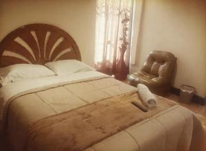 a bedroom with a large bed and a leather chair at Casona Kolivri in Arequipa