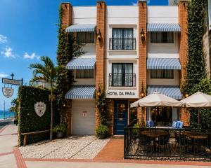 a building with tables and umbrellas in front of it at Hotel da Praia in Vila Velha