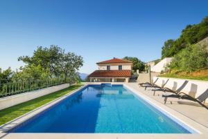 a swimming pool with chairs in front of a house at Villa Alba Moscenicka Draga in Mošćenice