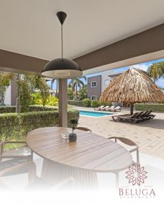 a patio with a table and a straw umbrella at Beluga Apartments Curacao - nabij Willemstad & Mambo Beach in Willemstad