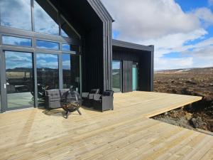 a black house with a wooden deck and glass windows at Aurora luxury villa in Reykholt