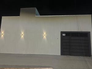 a white building with three lights on the wall at Conforto e praticidade em um só local in Rio Verde
