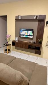 a living room with a flat screen tv on a wall at Casa Espaçosa e Aconchegante com 4 camas, 3 quartos in Juazeiro do Norte