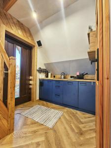a kitchen with blue cabinets and a wooden floor at Apartament Rysulówka 76 in Kościelisko +7 photos