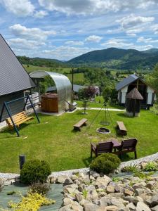 a backyard with a playground and a swing and a pond at Domki- Limanowa, domki z balią i sauną in Limanowa