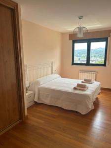 a bedroom with a white bed and a window at Piso moderno in Sarria