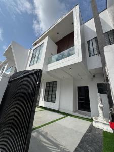 a white house with a black fence in front of it at Danjo Shortlets in Aja