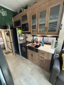 a kitchen with wooden cabinets and a black refrigerator at Bumblebee - Luxury Destination Trailer in Canyon Lake