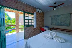 a bedroom with a bed with white sheets and a window at Pousada Boa Sorte in Cumuruxatiba +62 photos