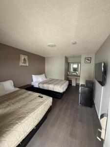 a hotel room with two beds and a flat screen tv at Monte Mario Motel & Efficiency in Latham