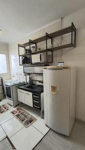 a kitchen with a refrigerator and a shelf with dishes at Refúgio perfeito em Itatiba in Itatiba