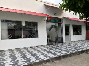 a white building with a checkered floor in front at Heliconias Hotel in Leticia