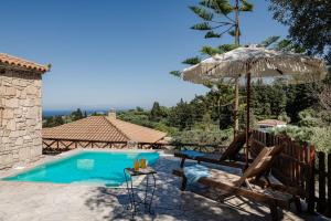 a swimming pool with an umbrella and chairs and a table at Vozas Villas - Traditional Houses with Great View in Tragaki