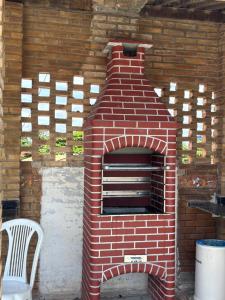 an outdoor brick oven with a chair next to it at Lugar de paz loft beira mar in Marechal Deodoro