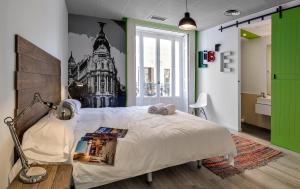 马德里Safestay Madrid Central的卧室配有一张白色的大床,墙上绘有建筑 更多37张照片