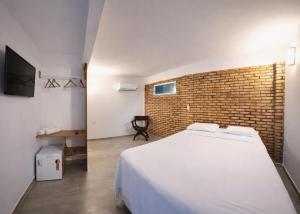 a bedroom with a white bed and a brick wall at Pousada Hope Club in Beberibe