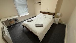 a bedroom with a large white bed and a desk at Stirling Steet in Wallasey