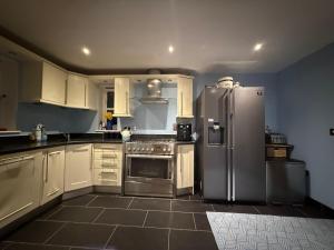 a kitchen with white cabinets and a stainless steel refrigerator at Silsoe B&B Master Suite in Silsoe