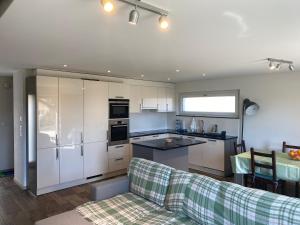 a kitchen with white cabinets and a couch in a living room at Bell Air-Plus in Les Hauts-Geneveys