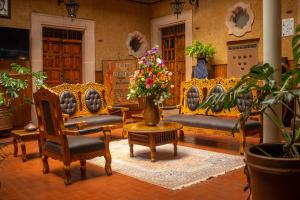 a living room with couches and chairs and flowers at Hotel Los Escudos in Pátzcuaro