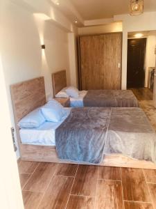 two large beds in a room with wooden floors at فلورنزا خمسين in Hurghada