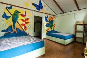 a bedroom with two beds and a bird painted on the wall at Cecropia Ecolodge in Fortuna