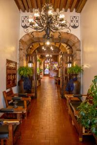 a hallway with tables and a chandelier in a building at Hotel Los Escudos in Pátzcuaro