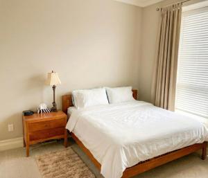 a bedroom with a bed with a nightstand and a window at Richmond 2-Bedroom Luxry Suite in Richmond