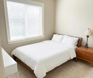 a white bed in a bedroom with a window at Richmond 2-Bedroom Luxry Suite in Richmond
